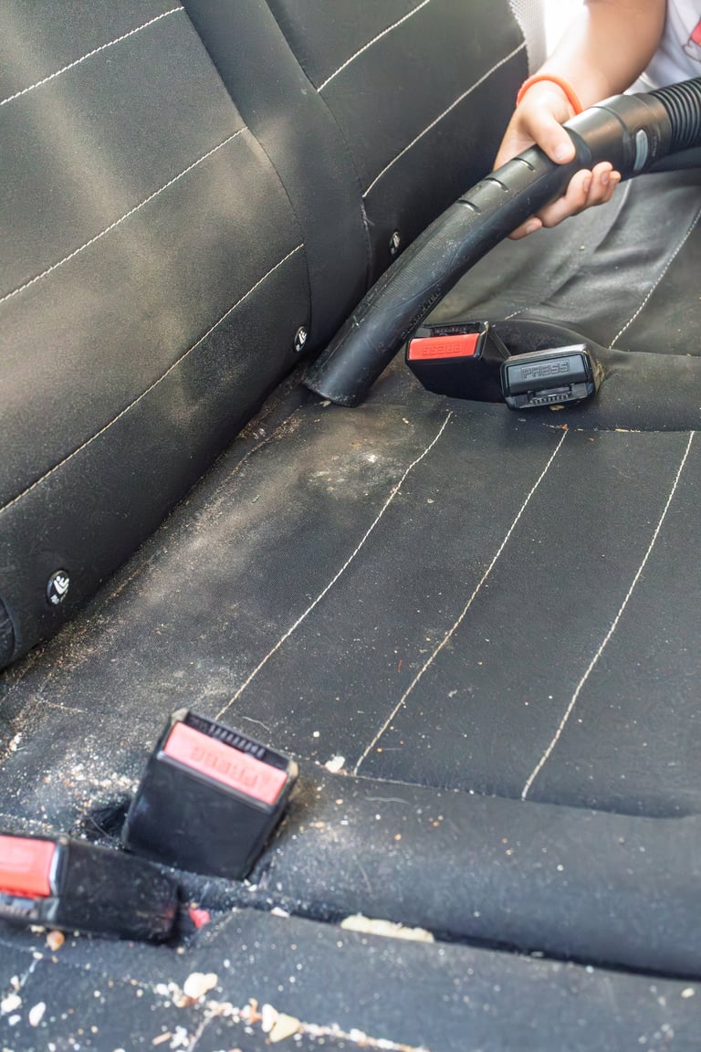 Person vacuuming car interior during detailing service
